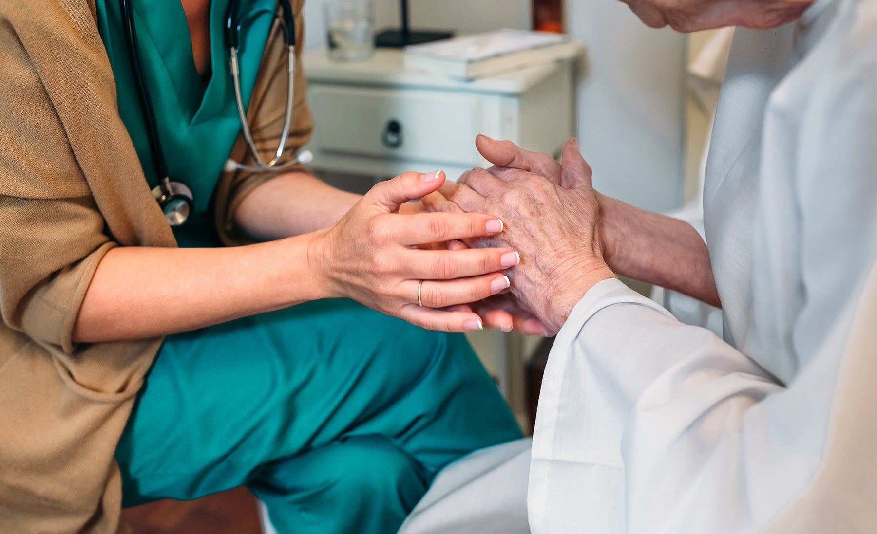 A doctor holding the hands of an elderly patient