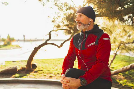 Man in a red jacket sitting outdoors, looking to the side in warm sunlight